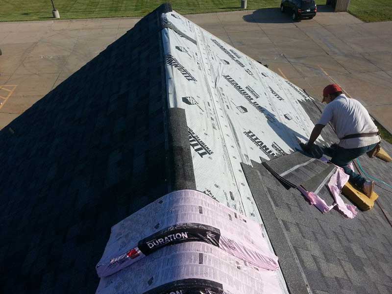 Action Roofing & Construction team member installing new gray shingles on a residential roof
