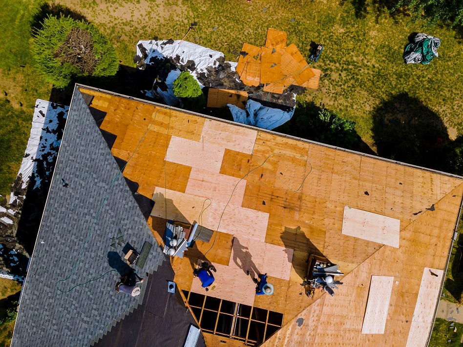 Aerial view of Des Moines roofing construction repairman on a residential apartment with new roof shingle being applied